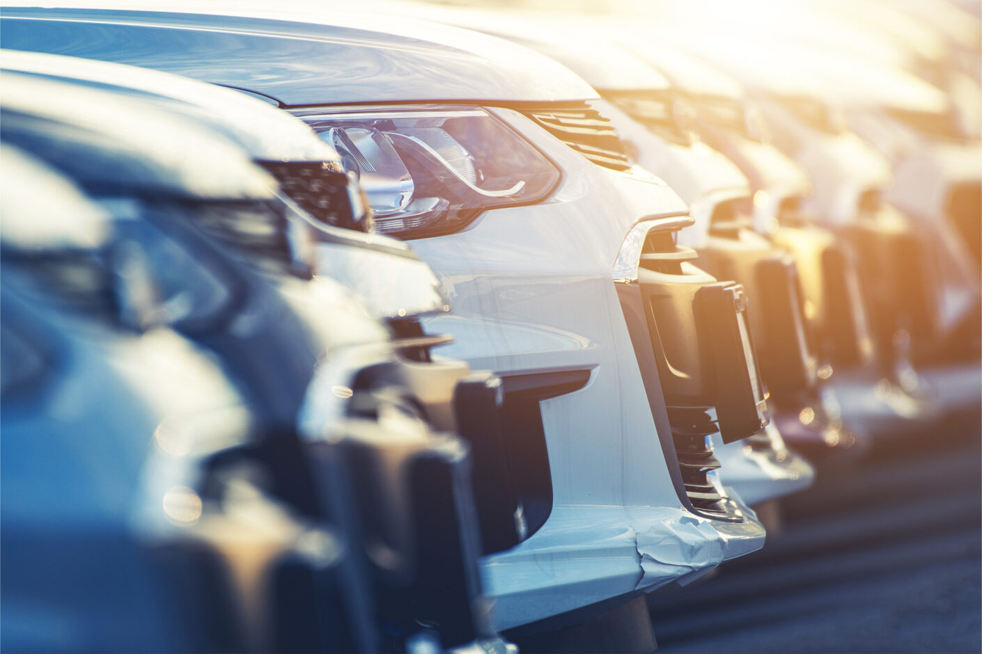 A line of cars in a dealership parking lot